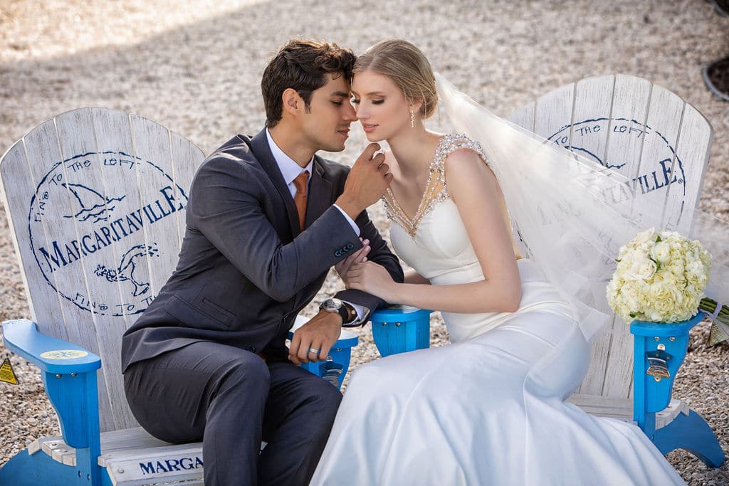 bride and groom in white and blue adirondack chairs on sand - margaritaville resort orlando wedding venue